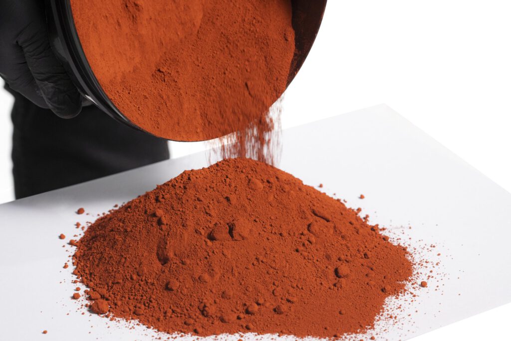 Hand pouring red powder onto white surface