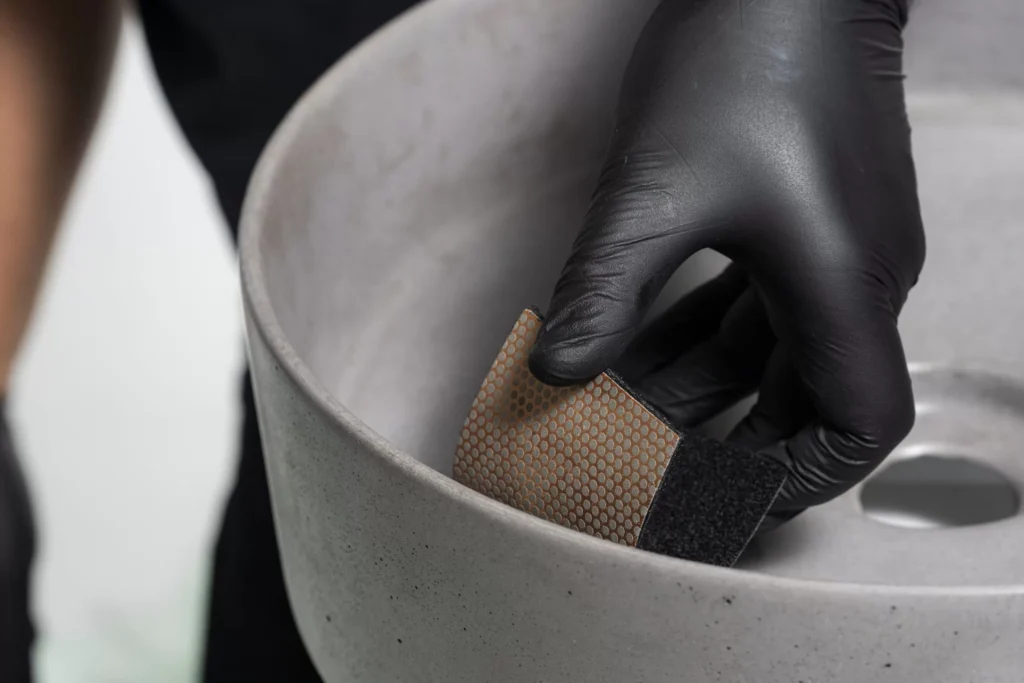 Person sanding a ceramic bowl.