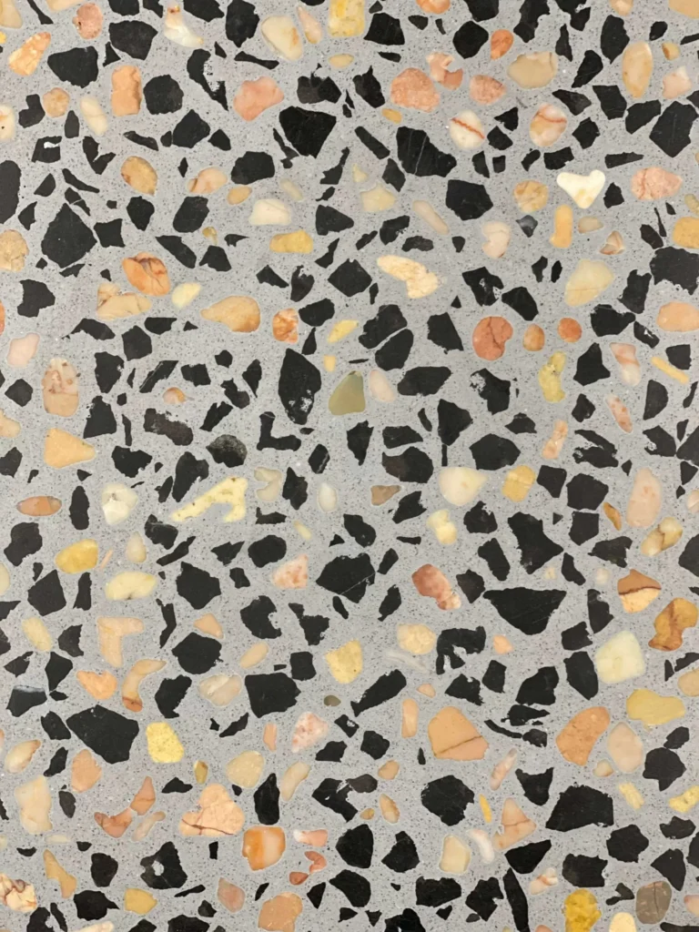 Multicoloured terrazzo tile pattern with black, beige, and grey.