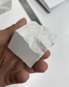 Person holding a white mineral cube.
