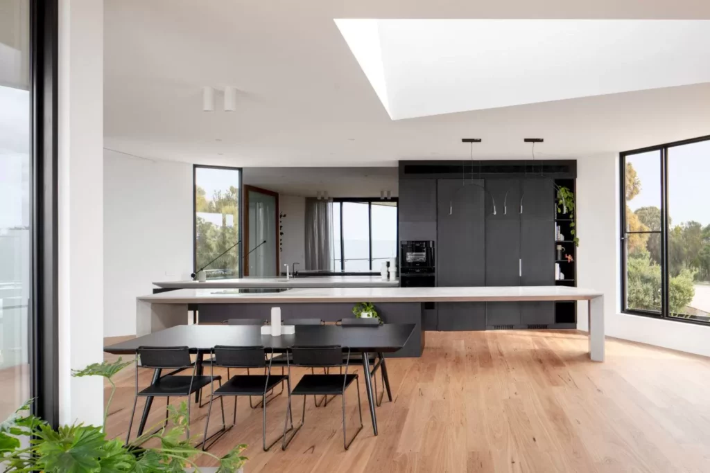 Modern kitchen with large windows and wooden floor.