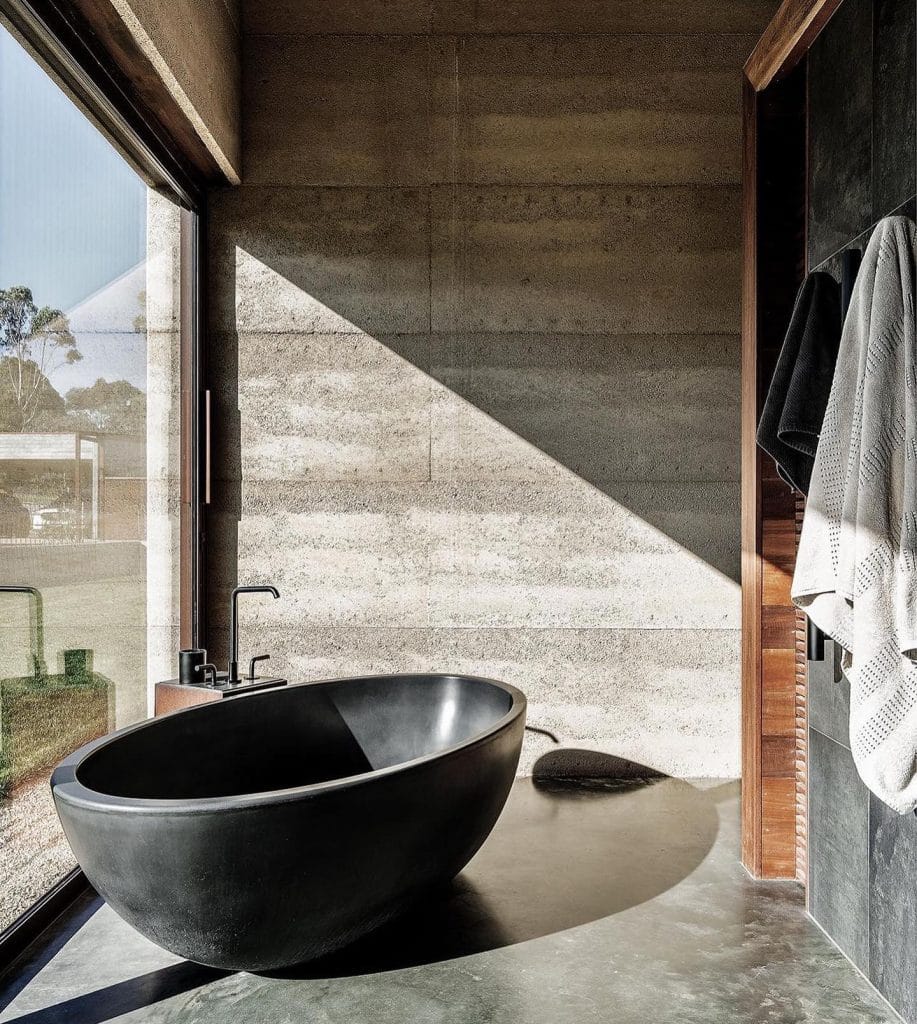 Modern bathroom with freestanding black bathtub and towels.