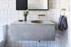Modern bathroom with concrete sink and brass fixtures.