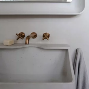 Modern bathroom sink with brass taps and grey towel.