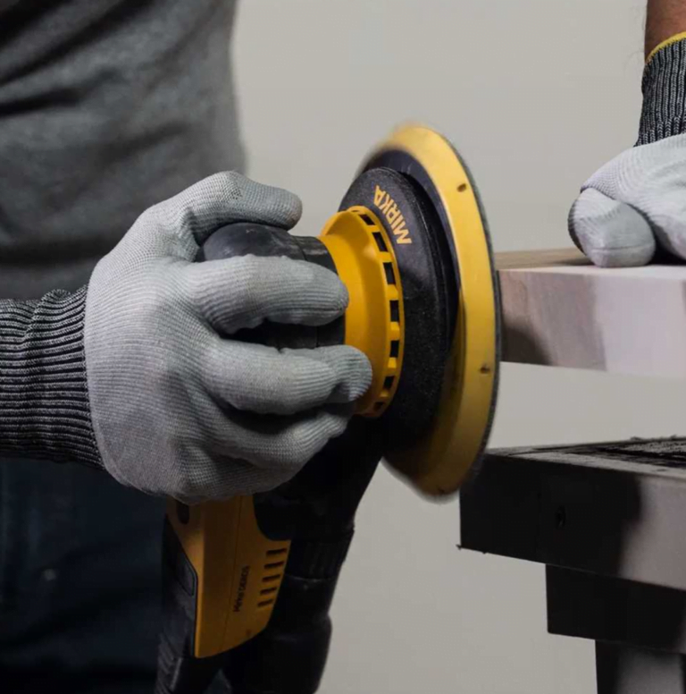 Person sanding wood with yellow electric sander.