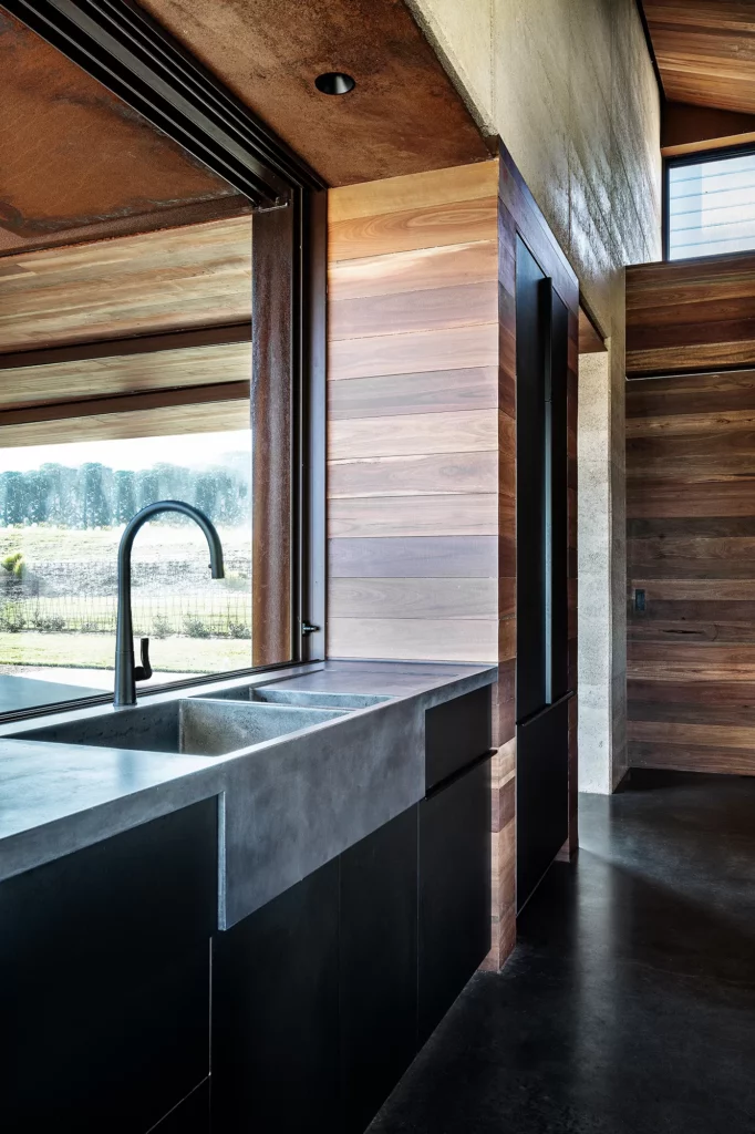 Modern kitchen with concrete sink, wood and glass design.