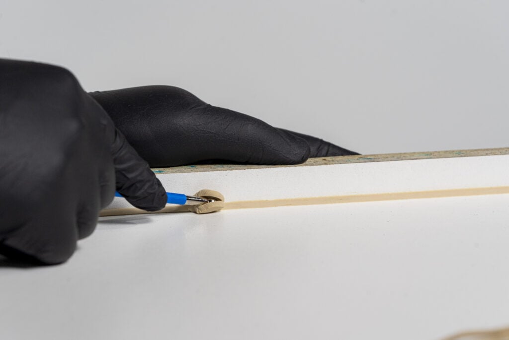 Gluing wood under black glove.