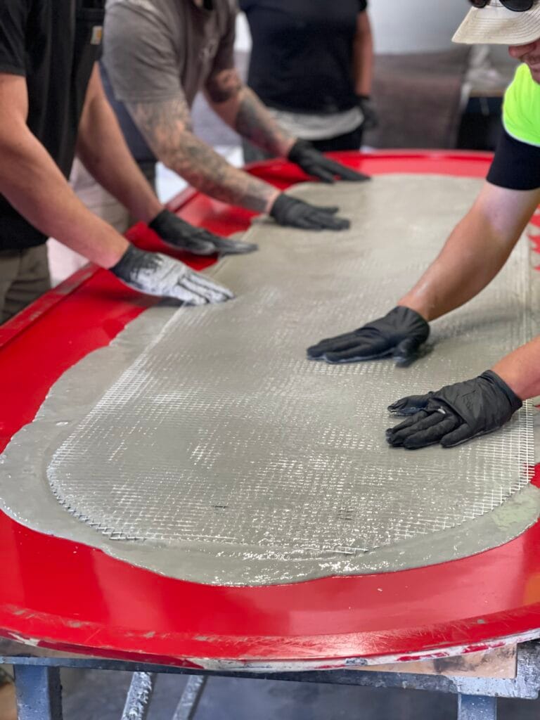 Workers smoothing concrete in fiberglass mold.