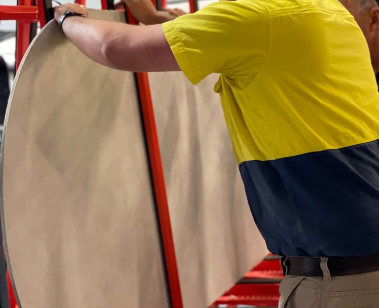 Worker handling large concrete panel on site.