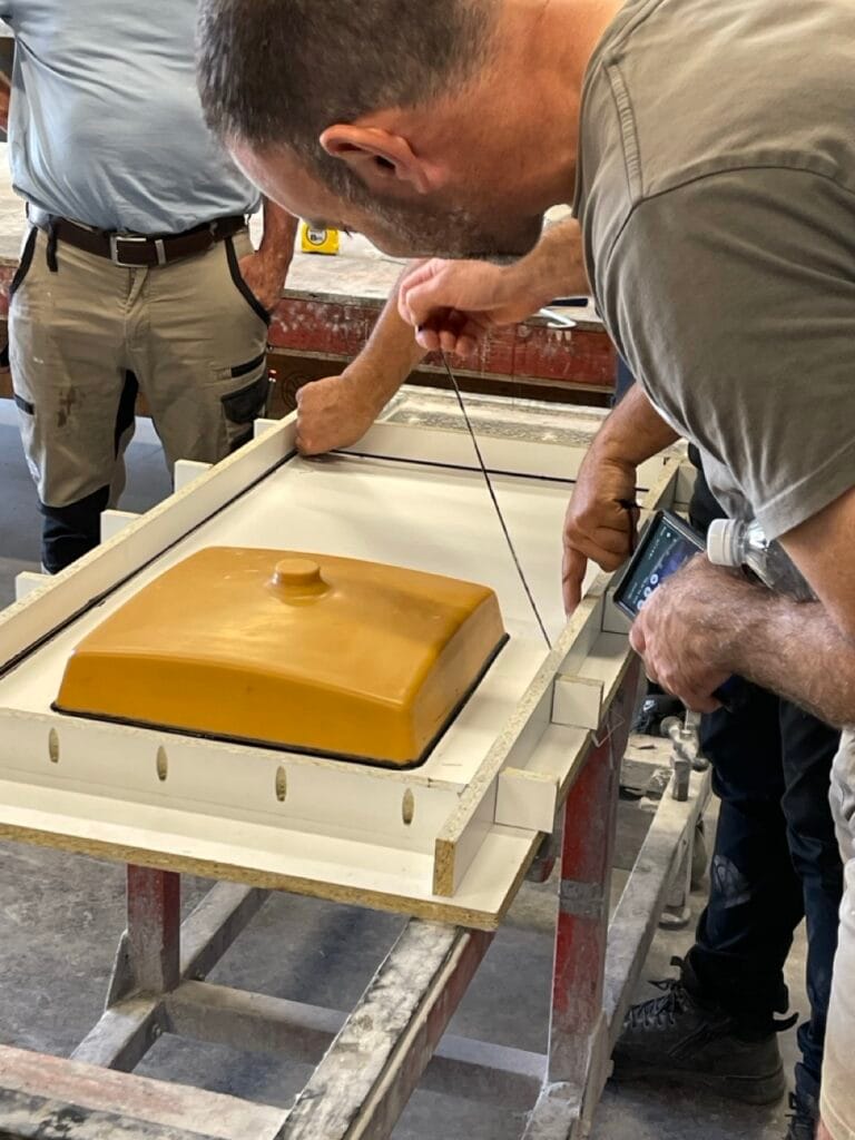 Men assembling yellow machinery part in workshop.