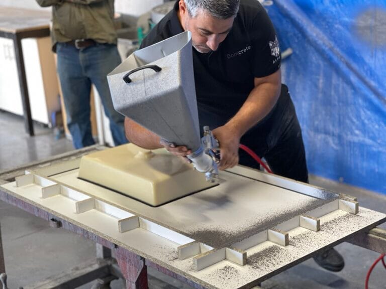 Man spraying concrete mould in workshop.
