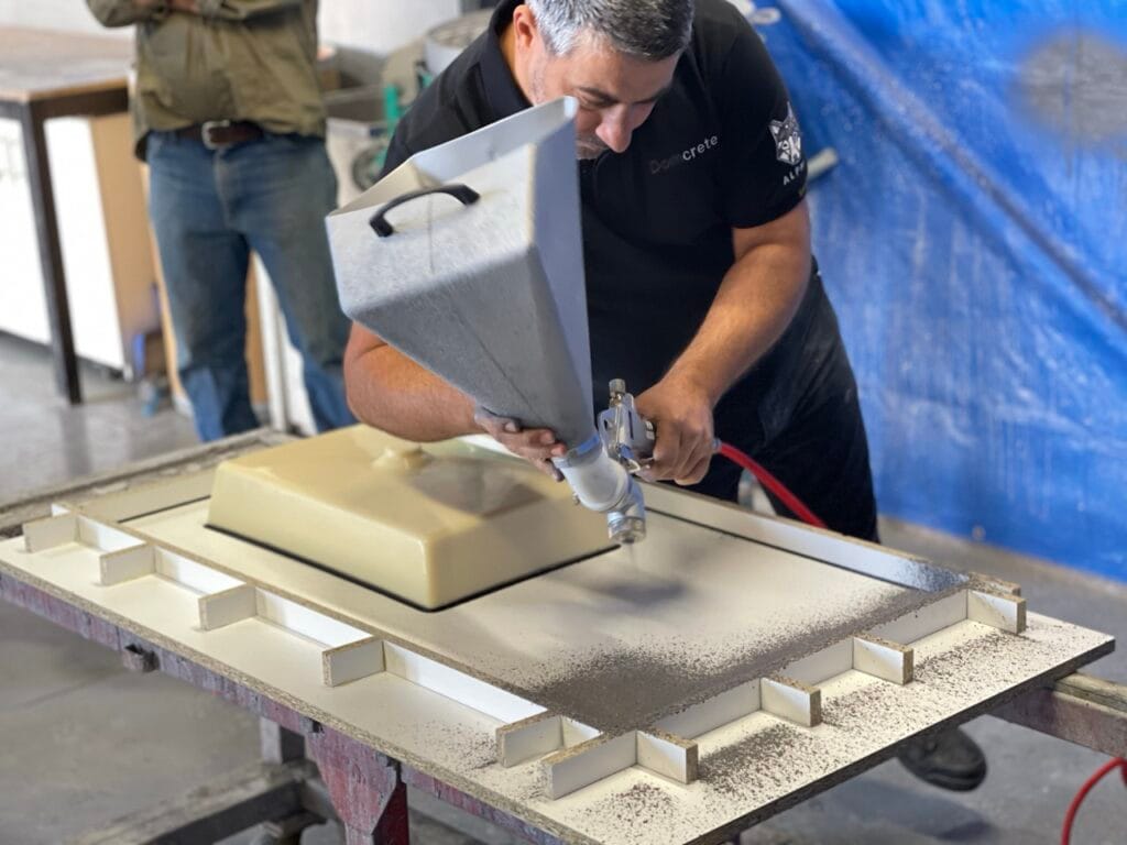 Man spraying paint on mould in workshop.