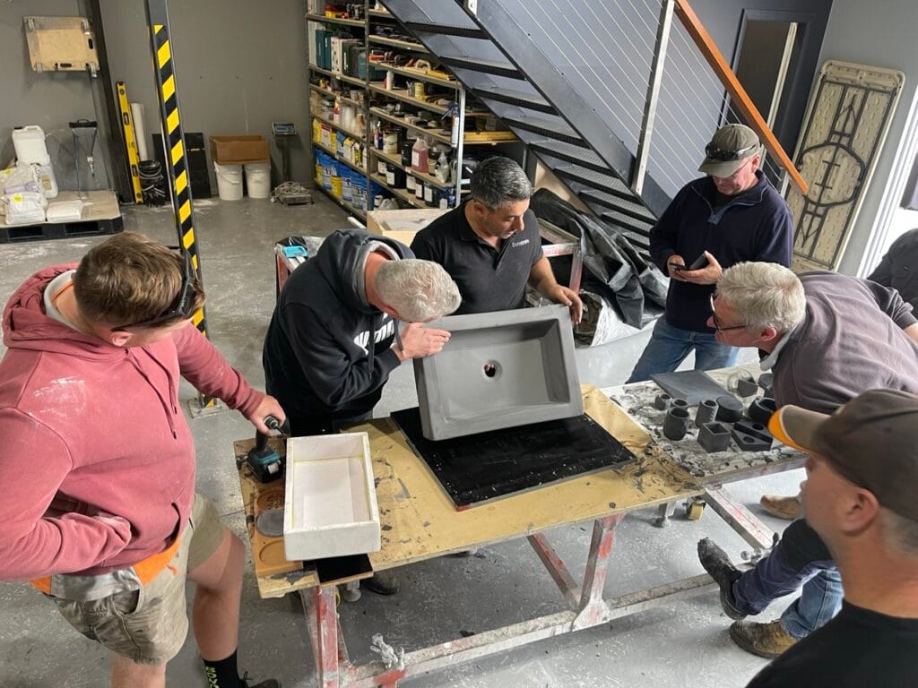 Men assembling concrete moulds in workshop.