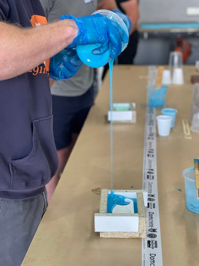 Person pouring blue resin into a mould.