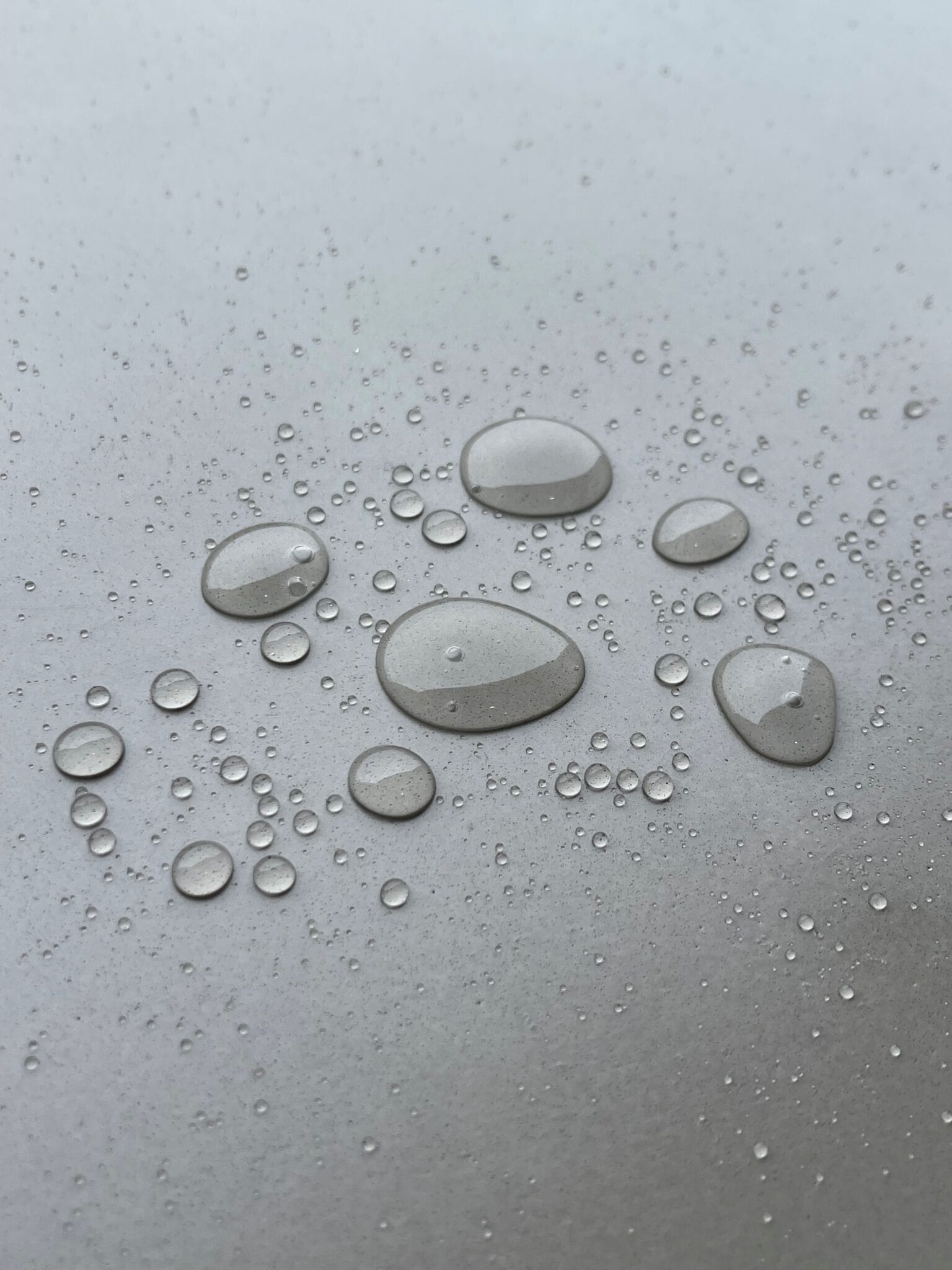 Close-up of droplets on a grey surface.